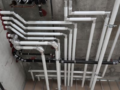 Red firestop caulk sealing pipe penetrations through a concrete wall installed by Metro Insulation Black, copper and insulated pipes with red firestop caulk sealing the penetrations through a concrete wall