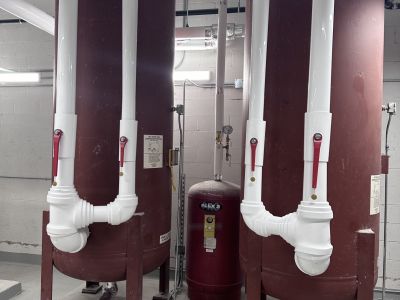 Insulated white PVC-jacketed pipe fittings around expansion tanks installed by Metro Insulation Hot water tanks before insulation